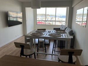 A dining area with a table, chairs, and a view of a marina. - At Germaine: Air-Conditioned Apartment with Ocean View (Six-Fours-les-Plages)