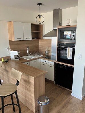 A modern kitchen with a wooden countertop, a built-in dishwasher, and a stainless steel oven. - At Germaine: Air-Conditioned Apartment with Ocean View (Six-Fours-les-Plages)