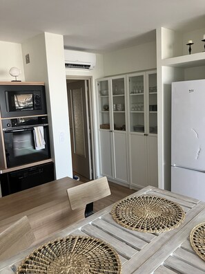 A modern kitchen with a dining table, cabinets, and a refrigerator. - At Germaine's: Air-conditioned apartment with a view of the sea (Six-Fours-les-Plages)