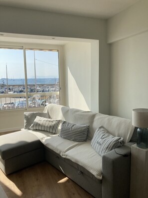 A modern living room with a large window overlooking a marina. - At Germaine: Air-Conditioned Apartment with Ocean View (Six-Fours-les-Plages)
