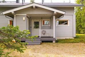 A two-story house with a front porch, a door with a window, and a small overhang above the door. - Villa Lumikenkä – Cozy Retreat & Private Sauna (Kuusamo)
