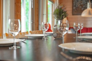 Une table à manger dressée avec des assiettes, des verres et un vase rempli de fleurs.