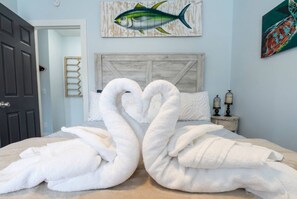 A bedroom with a bed, a wall-mounted fish painting, and a decorative wall piece. - Saltwater Heated Pool | Kayaks |Golf Cart | Firepit | Beach (Palm Coast)