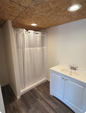 A bathroom with a shower curtain, a sink, and a wooden ceiling.
