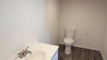 Une salle de bain avec un lavabo blanc, des toilettes et un plafond en bois.