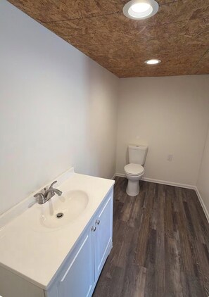 A bathroom with a white sink, a toilet, and a wooden ceiling.