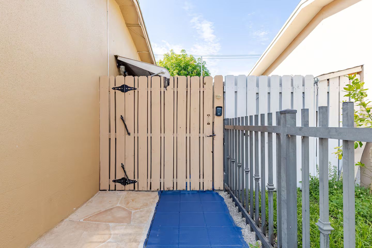 A gated entrance with a blue mat leading to a stone-paved area.