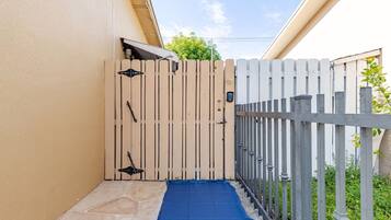 A gated entrance with a blue mat leading to a stone-paved area.