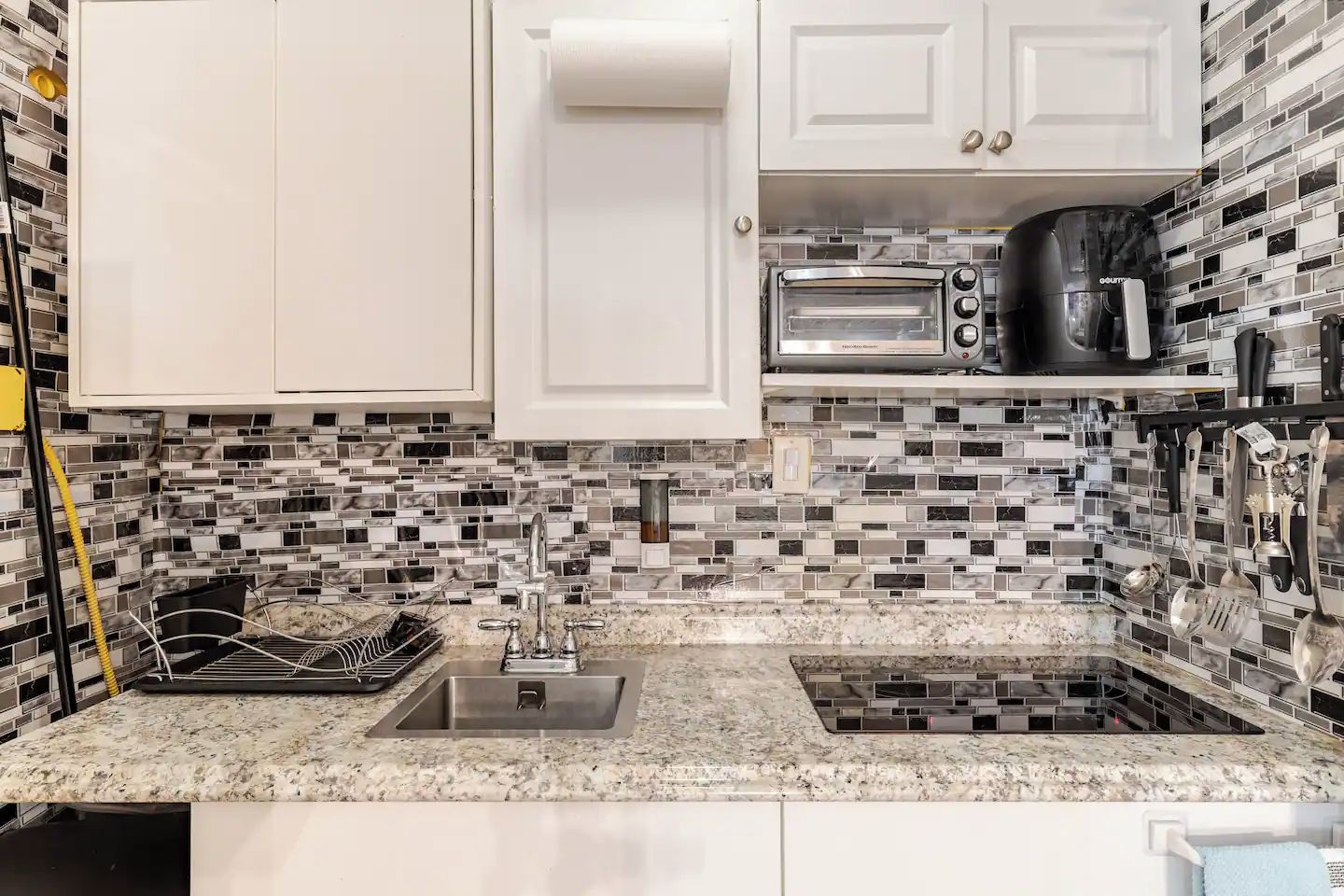 A kitchen with white cabinets, a double sink, a toaster, and a coffee maker.