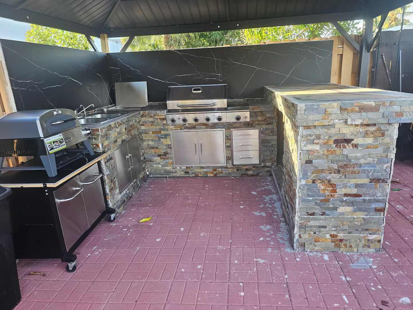 An outdoor kitchen with a grill, oven, and storage cabinets.