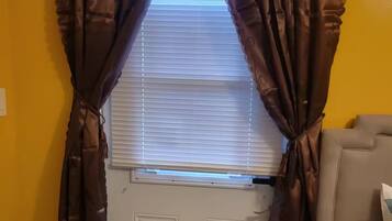 Una habitación con una puerta, una ventana con persianas y un sofá.