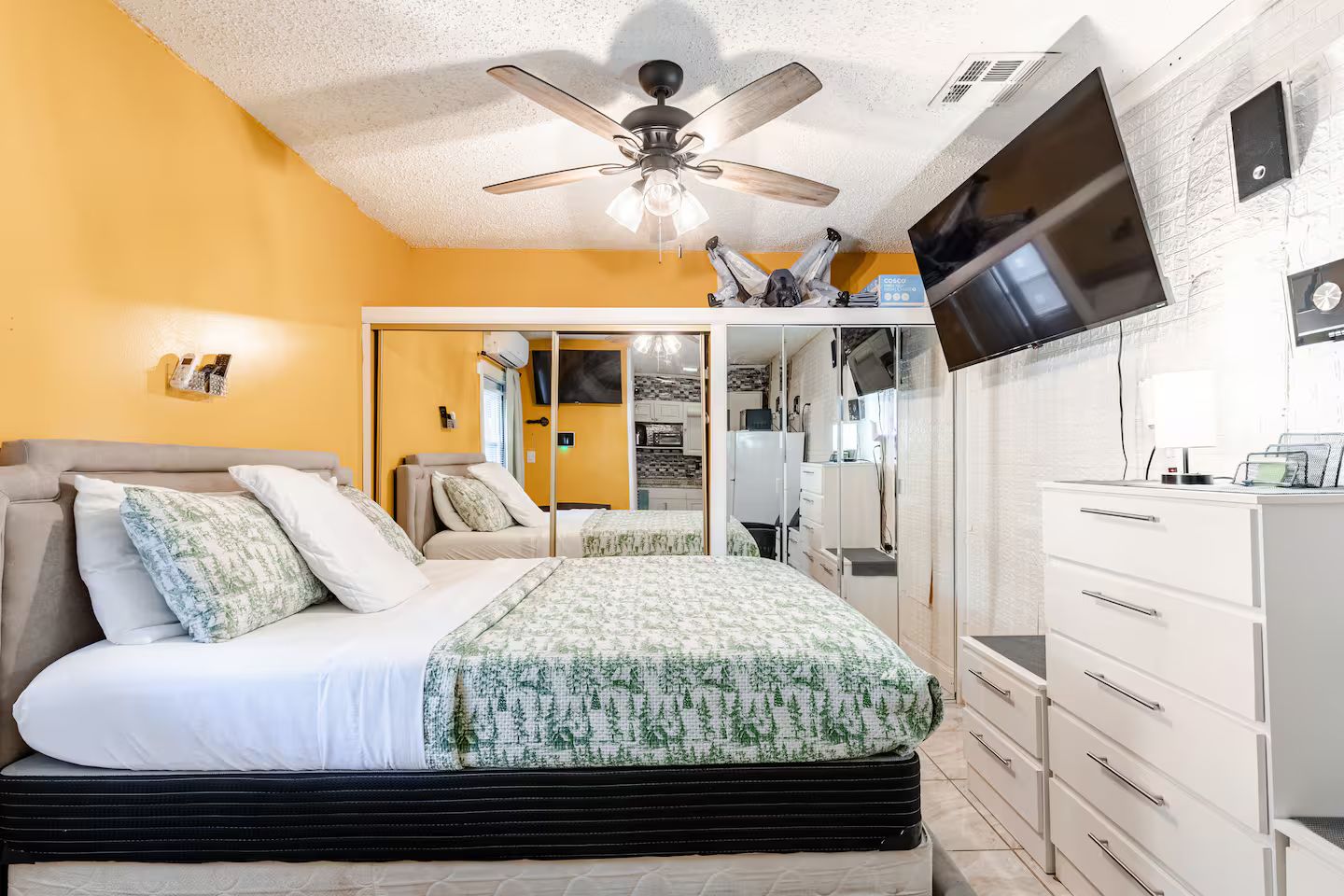 A bedroom with a bed, a ceiling fan, a TV, and a wardrobe.