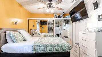 A bedroom with a bed, a ceiling fan, a TV, and a wardrobe.