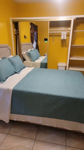 Une chambre avec deux lits, une armoire et une petite poubelle.