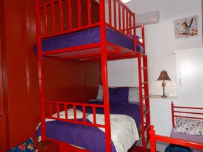 A bunk bed room with a red frame, a desk with a lamp, and a wall-mounted air conditioner. - Great Panoramic View Apartment B, Whale Hill. (Puerto Peñasco)