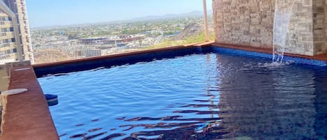 En indendørs swimmingpool med fliset gulv og udsigt til bybilledet.