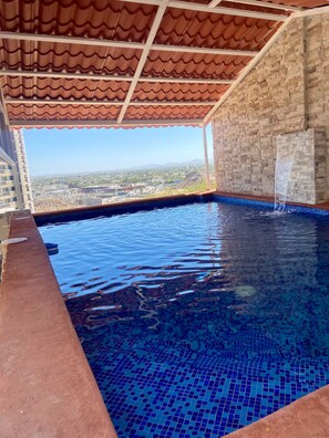 An indoor swimming pool with a tiled floor and a view of a cityscape. - Great Panoramic View Apartment B, Whale Hill. (Puerto Peñasco)