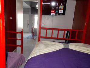 A hotel room with a bed, a TV mounted on the wall, and a red-framed window. - Great Panoramic View Apartment B, Whale Hill. (Puerto Peñasco)