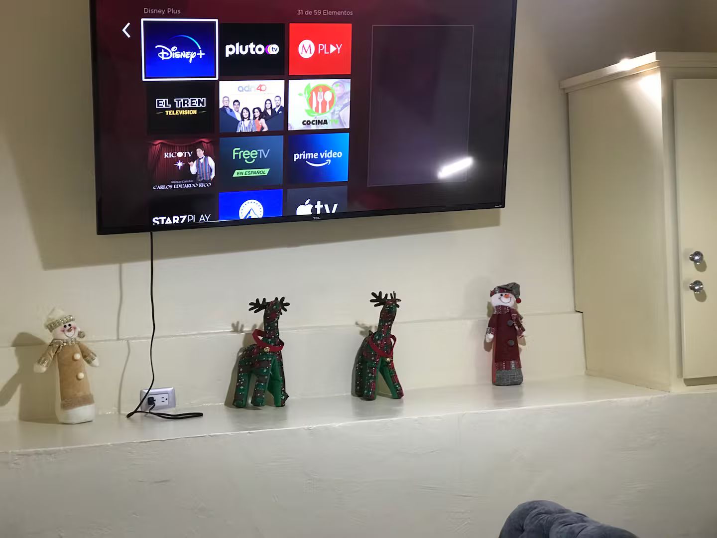 A television mounted on a wall displaying various streaming services.