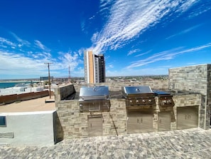 A rooftop with a barbecue area, stone flooring, and a view of the city and beach. - Great Panoramic View Apartment B, Whale Hill. (Puerto Peñasco)