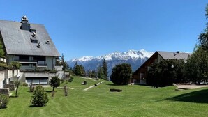 A residential area with houses, a well-maintained lawn, and a mountain range in the background.