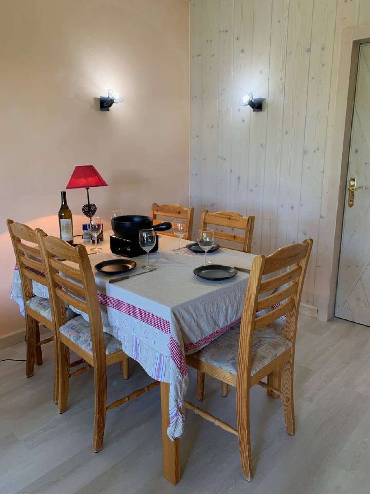 A dining table set with chairs, a wine bottle, glasses, and a heart-shaped decoration.