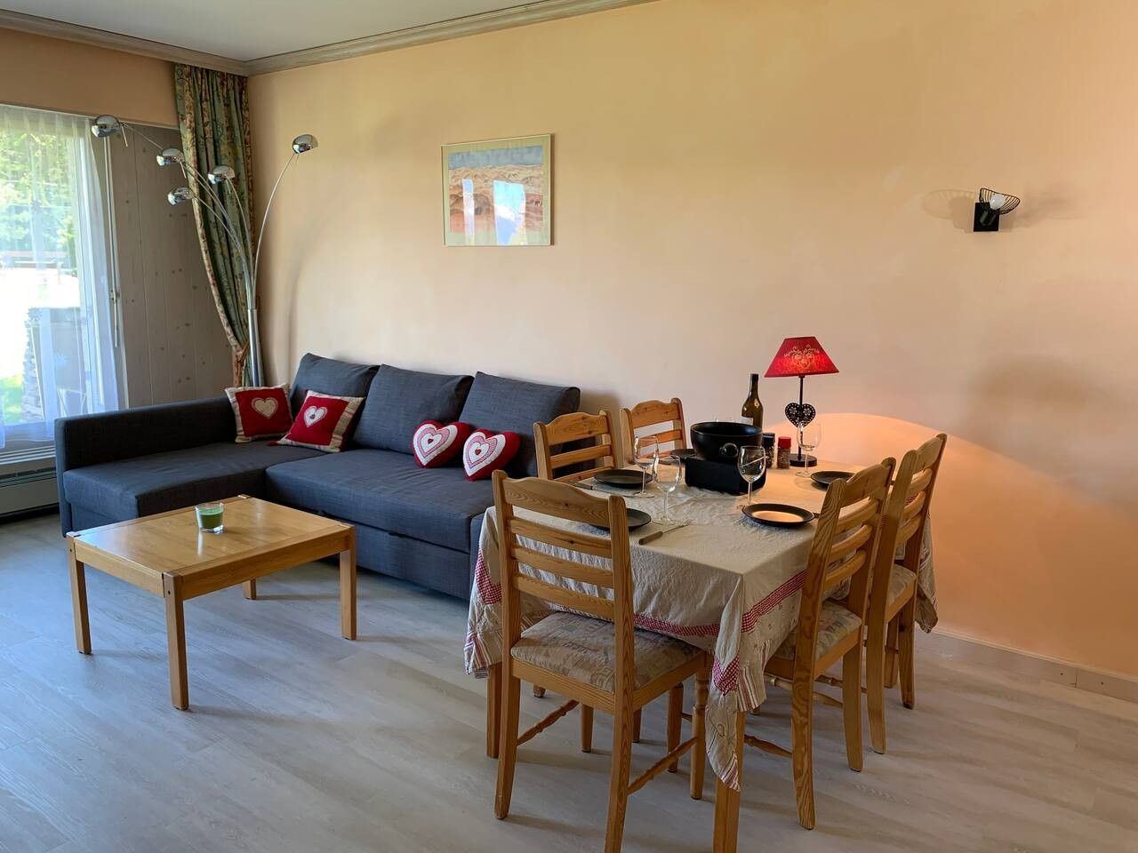 A living room with a sofa, a dining table with chairs, a coffee table, and a lamp.