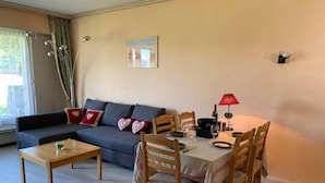 Ett vardagsrum med en soffa, ett matbord med stolar, ett soffbord och en lampa.