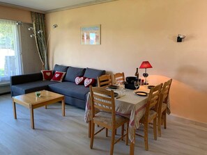 Un salon comprenant un canapé, une table à manger avec des chaises, une table basse et une lampe.