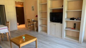 A living room with a wooden table, a sofa, and a TV on a cabinet.