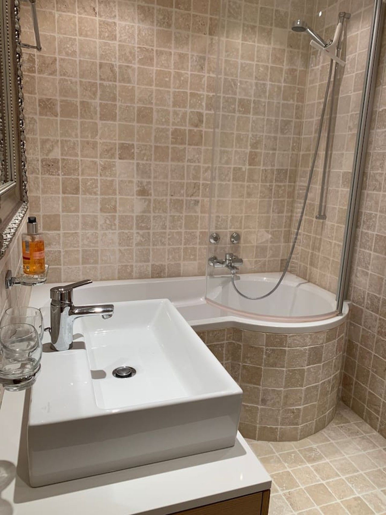 A bathroom with a white sink, a glass shower enclosure, and a mirror.