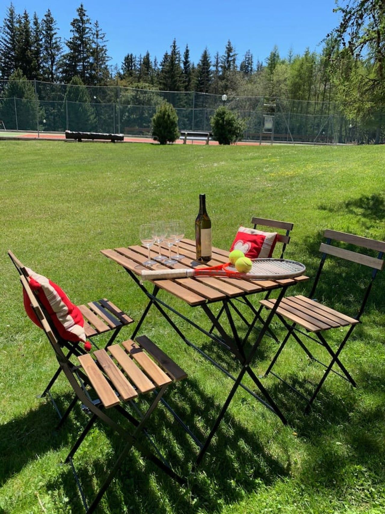 An outdoor seating area with a table, chairs, and a bottle of wine.