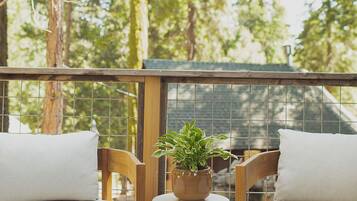 A wooden deck with two chairs and a potted plant.