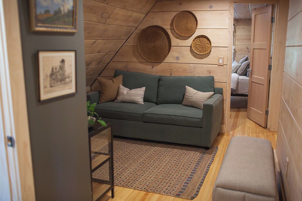 A cozy room with a green sofa, a wooden ceiling, and a small table with a plant.