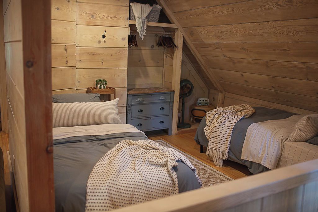 Un dormitorio acogedor en el ático con dos camas, un aparador y una mesita.