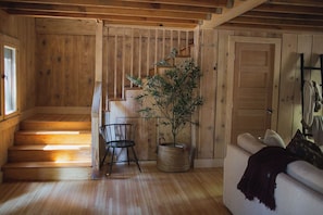 Un interior de madera con una escalera, un sofá y una planta en maceta.