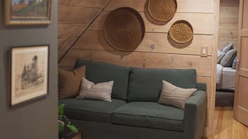 Una sala de estar acogedora con un sofá verde, un tapiz de pared tejido y un cuadro enmarcado.