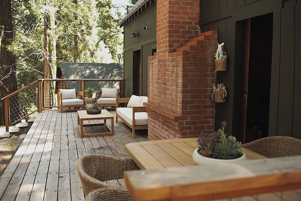 Una terraza de madera con mobiliario exterior, una pared de ladrillo y una maceta colgante.