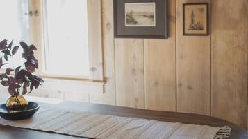 A wooden dining table with a woven placemat, black chairs, and a hanging pendant light.