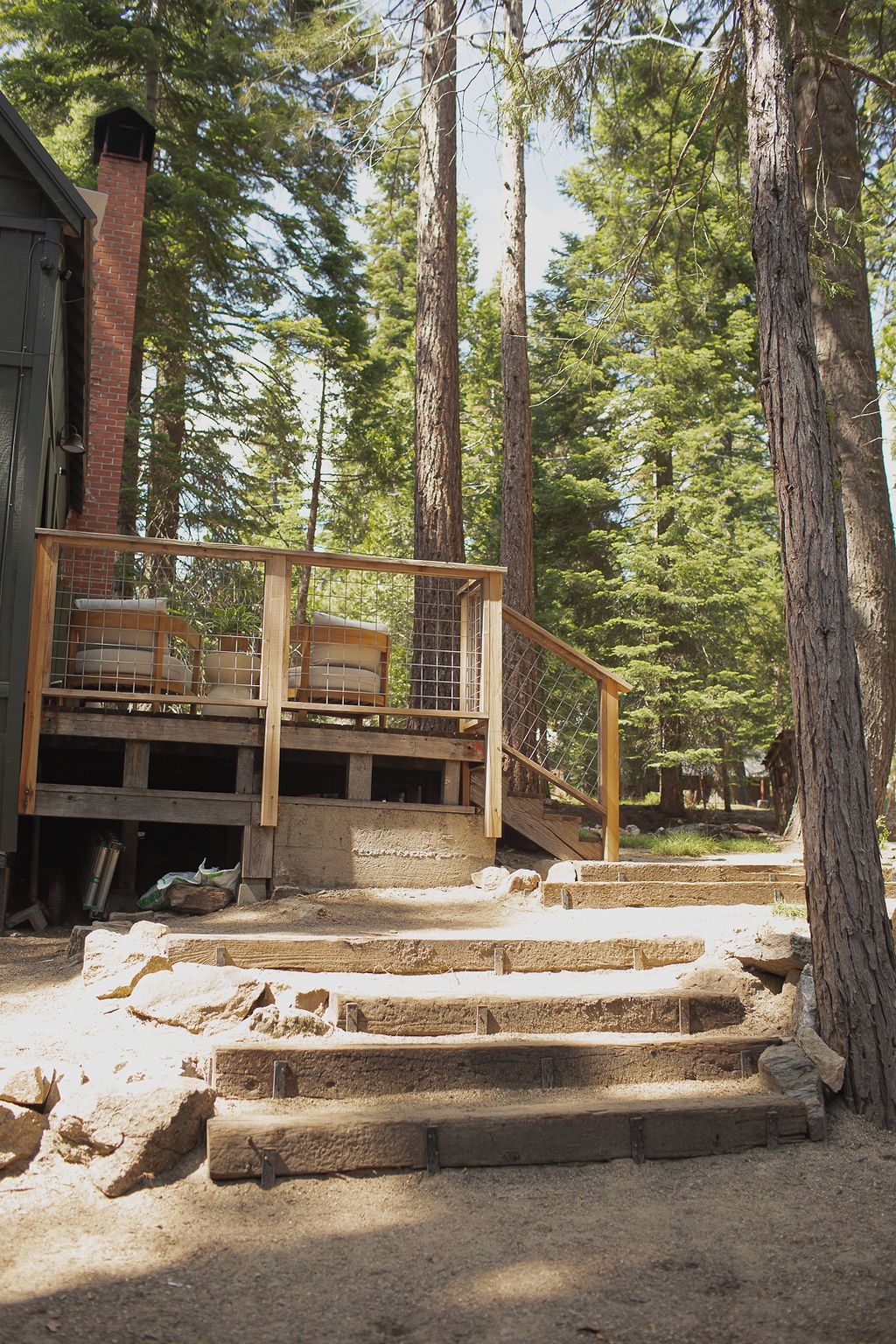 A wooden deck with outdoor seating, surrounded by trees.