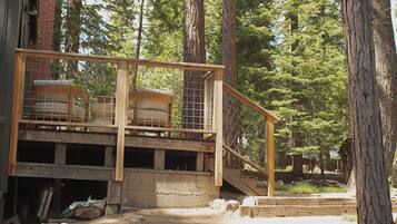 A wooden deck with outdoor seating, surrounded by trees.