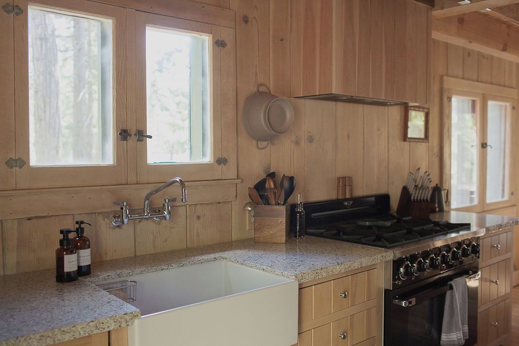 A kitchen with wooden cabinets, a granite countertop, a sink, a stove, and a window.