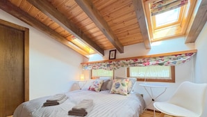 Una camera da letto con un letto grande, una sedia bianca e un lucernario.