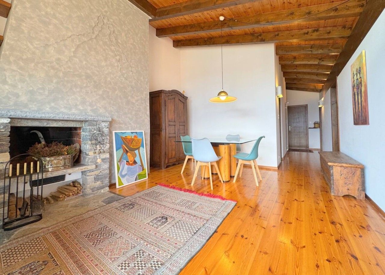 Un vaste espace de vie doté d’une cheminée, d’une table à manger avec des chaises et d’un grand tapis.