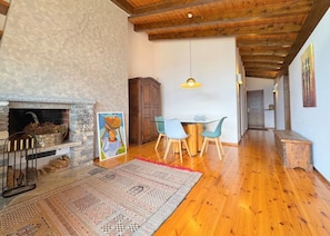 Un salón amplio con chimenea, una mesa de comedor con sillas y un tapete grande.