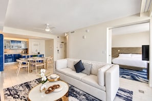 Ein modernes Hotelzimmer mit einer Sitzecke, einem Essbereich, einer Küche und einem separaten Schlafzimmer mit Bett und Fernseher.