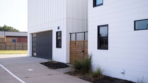 A modern building with a garage door, a wooden fence, and a paved driveway.