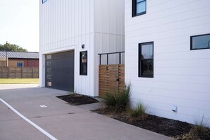 A modern building with a garage door, a wooden fence, and a paved driveway.