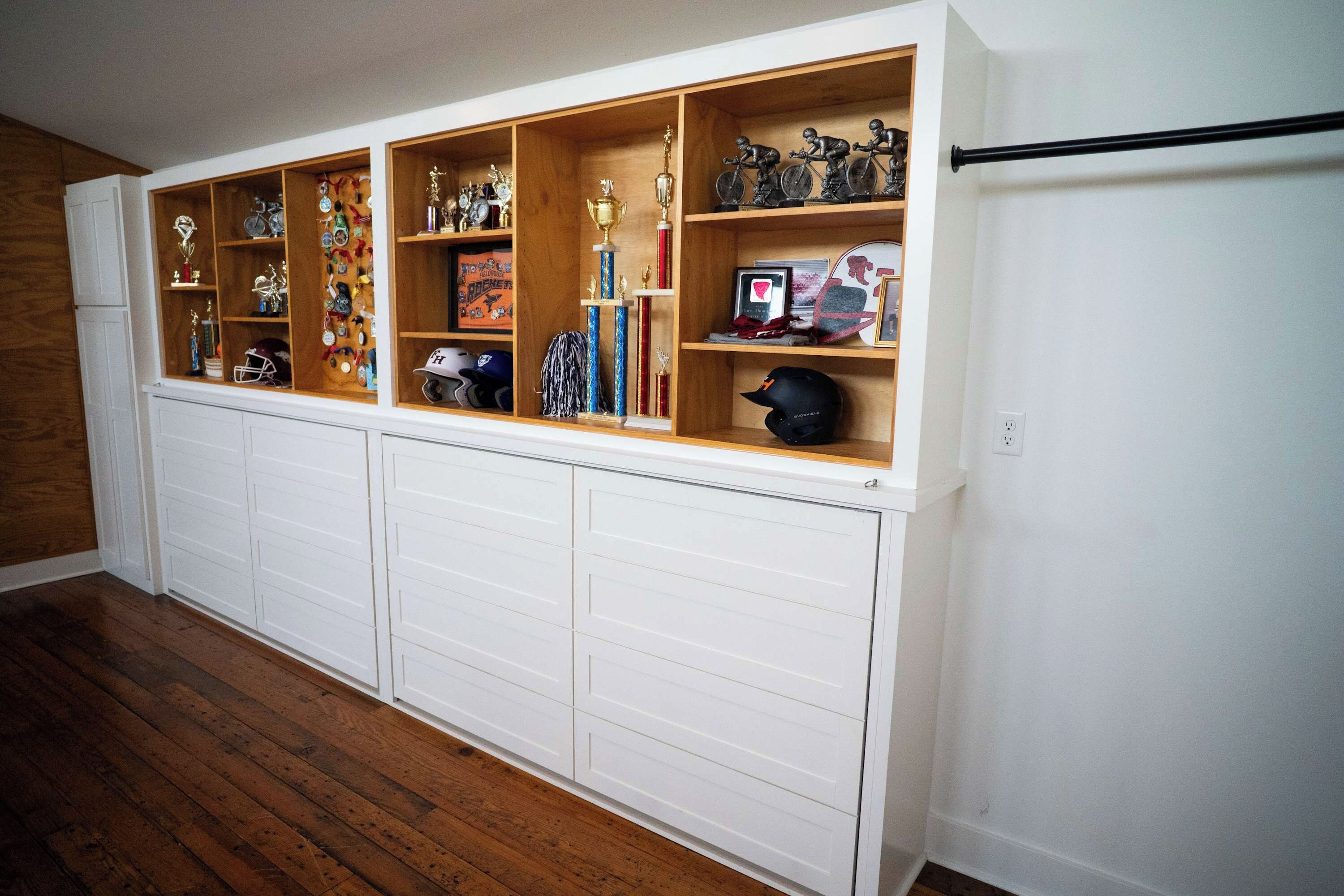 A garage with wooden shelving units displaying trophies, helmets, and sports memorabilia.