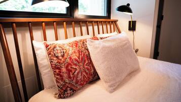 Una cama con cabecera de madera, dos almohadas y una lámpara de noche.